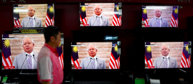 
A man passes a live telecast of Malaysias Prime Minister Najib Razak addressing the nation on the dissolution of Parliament at an electronics shop in Port Klang, Malaysia April 6, 2018. REUTERS/Lai Seng Sin
