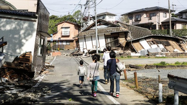 
People walk among houses destroyed by the 7.0 magnitude earthquake that hit Kumamoto, Japan on April 16, 2016. The day after a 6.2 magnitude foreshock on April 14, the Kumamoto prefecture was struck again (Taro Karibe/Getty Images)
