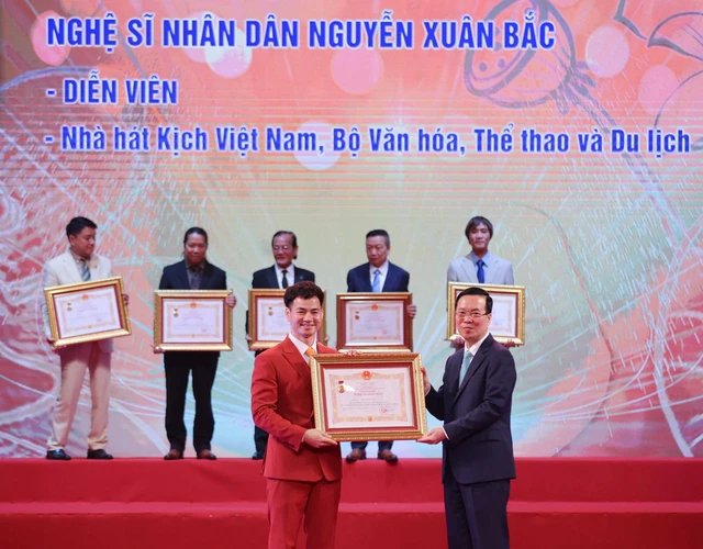 
Peoples Artist Nguyen Xuan Bac receives the title bestowed by the President. The title is given as an encouragemento artists to create works with values of morality, goodness, and beauty. (Photo: VNA)
