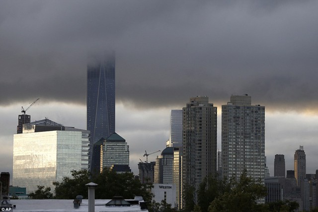 Low clouds surround the top of the One World Trade Center tower, center left, at sunrise during the 14th anniversary of the terrorist attacks, Friday, September 11, 2015, seen from The Heights neighborhood of Jersey City, New Jersey