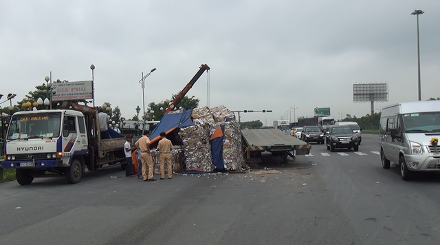 Lật xe đầu kéo, hàng tấn giấy vụn đổ tràn xuống đường dẫn cao tốc - Ảnh 1.