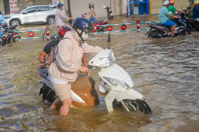 Tình nguyện viên dầm mưa, lội nước giúp người dân trong triều cường - Ảnh 1.