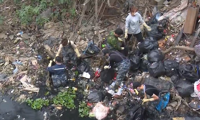 Thanh niên tình nguyện ngâm mình nhiều giờ dưới sông đen kịt để vớt rác - Ảnh 1.