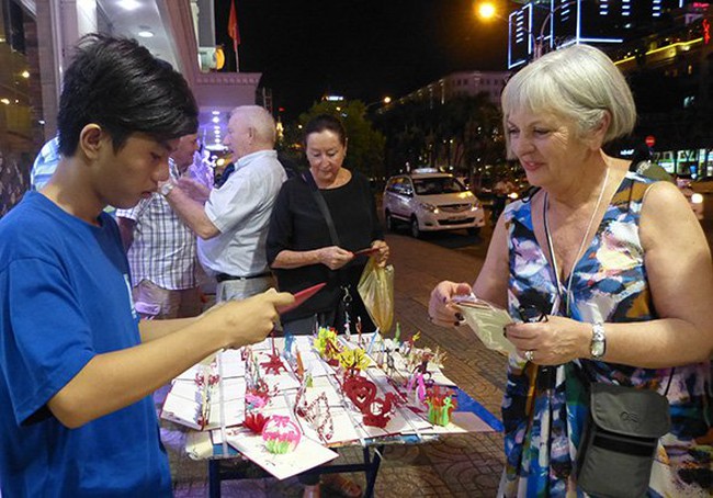 A local vendor sells a souvenir to a foreign tourist in HCMC. A survey shows foreign tourists do not easily recognize Vietnamese smiles - PHOTO: UYEN VIEN