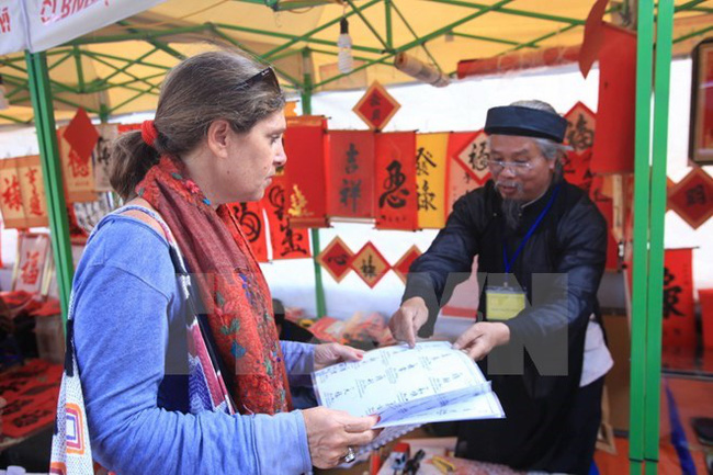 A calligrapher (R) and a visitor at the 2014 festival (Photo: VNA)