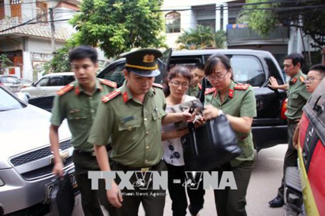 Police officers escort Nguyen Thi Hong Nga, 51, a member of the examination and quality management office under the Son La Department for Education and Training. (Photo: VNA)