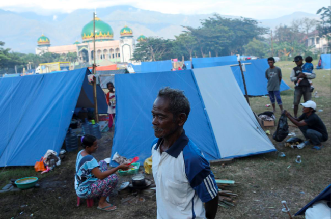 Gumbu, 73, stands with is family out his tent at a camp for displaced victims of the earthquake and tsunami in Palu, Central Sulawesi, Indonesia. (Photo: Reuters)