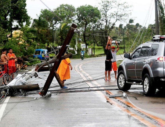 Filipino villagers lift electric wires in the typhoon-hit town of Lal-lo, Cagayan province, Philippines, Sept. 15, 2018.