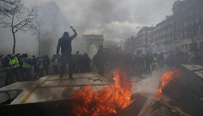 A protester stands on a burning barricade during a demonstration by the 