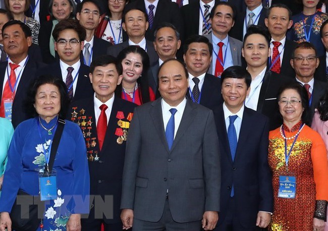 Prime Minister Nguyen Xuan Phúc (front, C) takes photo with overseas Vietnamese (Photo: VNA)