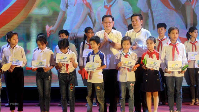 Deputy PM Vuong Dinh Hue (L) presents the relief packages to local students at the gala. (Photo: VNA)