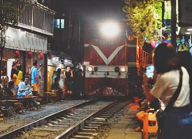 Tourists capture the moving train from coffee shops along both sides of the railway tracks in the Hanoi's Old Quarter.
