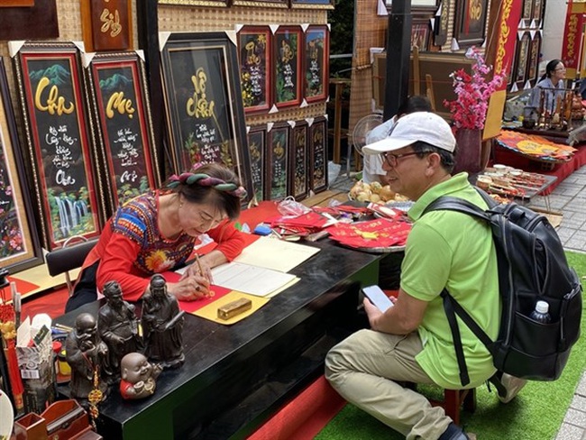 A visitor buys calligraphy works to wish for luck, happiness and prosperity in Tet (Photo: VNA)