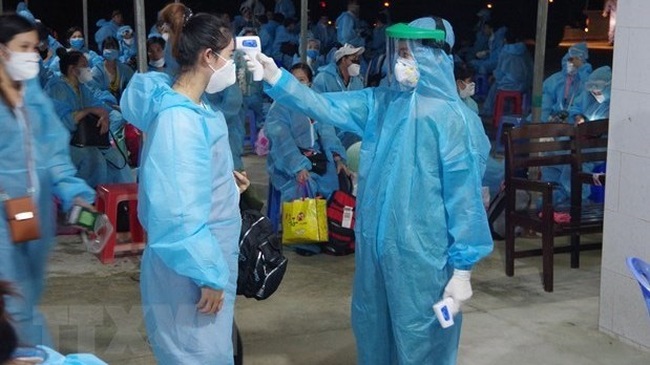 Vietnamese citizens returning home from abroad have body temperature checked before entering a concentrated quarantine establishment (Photo: VNA)