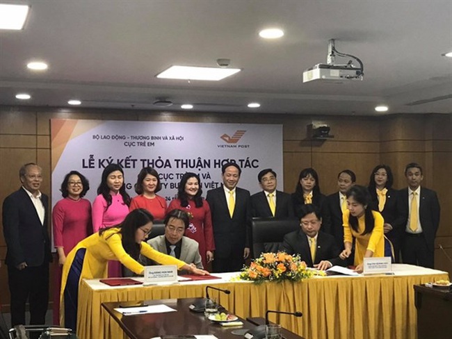 Dang Hoa Nam, Director of the Department of Child Affairs (sitting, left) and Chu Quang Hao, General Director of the Vietnam Post (sitting, right), sign the cooperation agreement. (Photo: VNA)