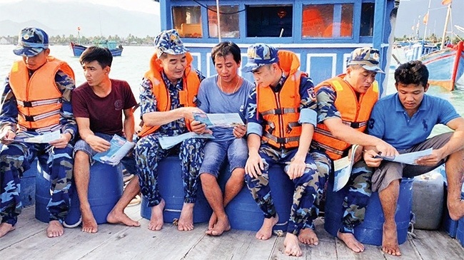 Officers of the Coast Guard Region 3 Command (under the Vietnam Coast Guard Command) distribute leaflets to inform fishermen about things they should know when fishing off-shore in Vietnamese waters.