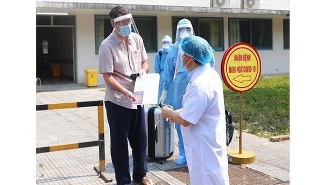 Prof., Dr. Pham Nhu Hiep (R), Director of Hue Central Hospital, presents a certificate of discharge to the 33rd COVID-19 patient, recognising his fully recovery from the disease, Phong Dien District, Thua Thien - Hue Province, March 28, 2020.