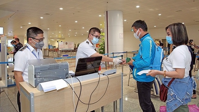Medical personnel check passengers' medical declarations before completing their entry procedures at Noi Bai International Airport. (Photo: NDO/Duong Giang)