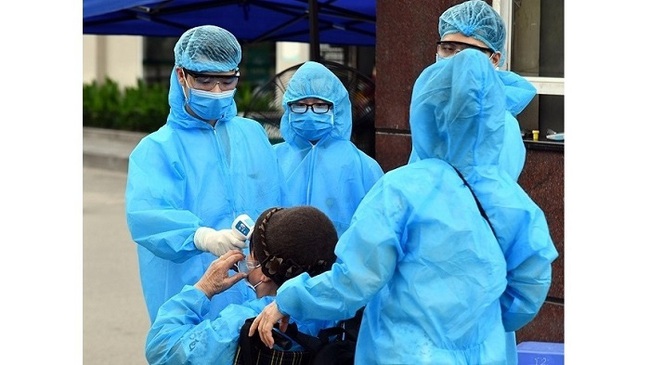 Health workers measure body temperature and carry out disinfection on a patient before entering Bach Mai Hospital in Hanoi. (Photo: NDO/Duy Linh)