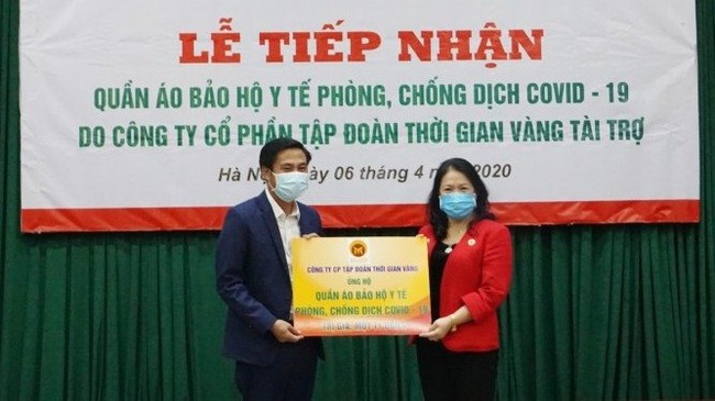 General Director of Golden Time Group Nguyen Khac Doi (left) hands over medical protective suits to President of the Vietnam Red Cross Society Nguyen Thi Xuan Thu.