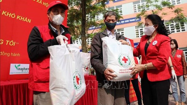President of the Vietnam Red Cross Society Nguyen Thi Xuan Thu (R) presents gifts to poor people to help them overcome the impact of COVID-19. (Photo: VNA)