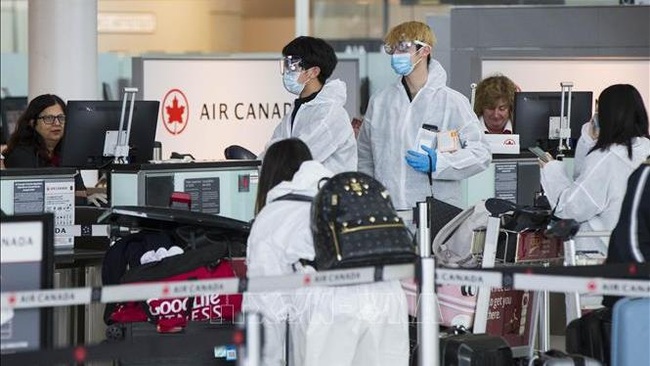 Tourists wear face masks to prevent COVID-19 at the Toronto Pearson International Airport in Toronto, Canada on April 14, 2020. (Photo: VNA)