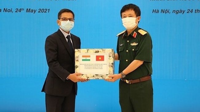 Lieutenant General Vu Chien Thang (R) presents the token of medical supplies to Indian Ambassador to Vietnam Pranay Verma (Photo: qdnd.vn)
