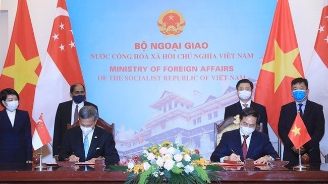 Singapore Foreign Minister Vivian Balakrishnan (first from left, front row) and Vietnamese Foreign Minister Bui Thanh Son sign an agreement on training for senior officials of the Communist Party of Vietnam in 2021-23. (Photo: VNA)