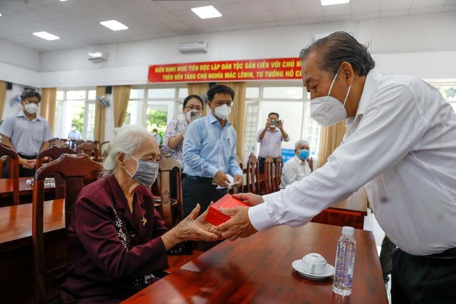 Permanent Deputy Prime Minister Truong Hoa Binh (first, right) presents a gift to Heroic Mother Vo Thi Tuoi. (Photo: VNA)
