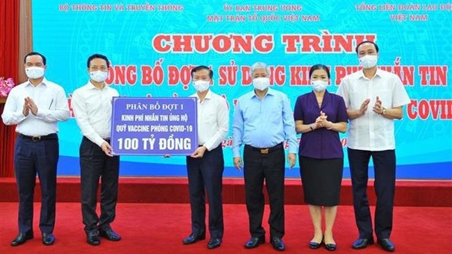 Minister of Information and Communications Nguyen Manh Hung (second from left) presents 100 billion VND donated to the COVID-19 vaccine fund via text messages to Director of the fund's management board Nguyen Quang Vinh (Photo: VNA)