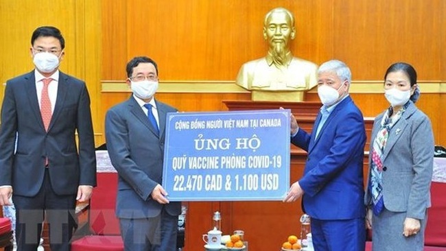 President of the Vietnam Fatherland Front Central Committee Do Van Chien (second, right) receives donations to the COVID-19 vaccine fund from the Vietnamese community in Canada on December 15 (Photo: VNA)