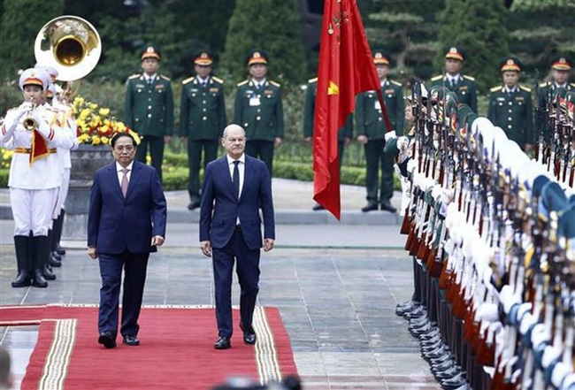 Children welcome German Chancellor Olaf Scholz (R) at the official welcome ceremony in Hanoi on November 13. (Photo: VNA)