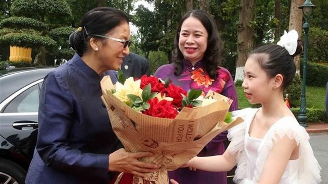 Lao Vice President Pany Yathotou (L) receives a bouquet from a Vietnamese girl. (Photo: VNA)