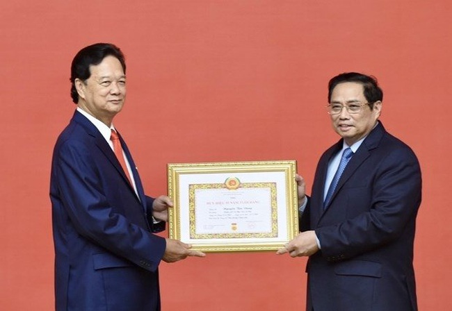 Prime Minister Pham Minh Chinh (R) presents the insignia to former Politburo member and former Prime Minister Nguyen Tan Dung. (Photo: VNA)