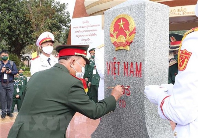 Lao Deputy Prime Minister and Defence Minister General Chansamone Chanyalath paints landmarker 605 at Lao Bao border gate in December 2021. (Photo: Trong Duc/VNA)