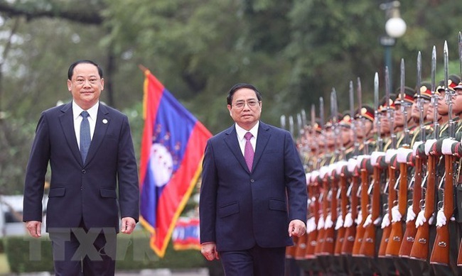 Prime Minister Pham Minh Chinh (R) and his Lao countepart Sonexay Siphandone review the guard of honour at the welcome ceremony for the Vietnamese leader in Vientiane on January 11 morning. (Photo: VNA)