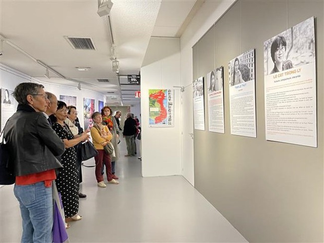 Visitors look at the portraits of 11 Vietnamese women from all walks of life by French journalist Sabrina Rouillé on display at the exhibition. (Photo: VNA)