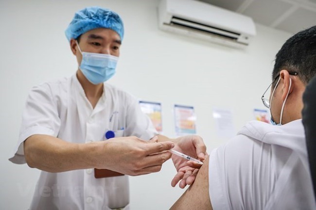 A health staff injects a dose of COVID-19 vaccination for a man. (Photo: VNA)