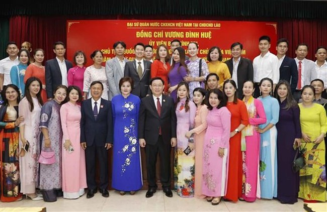 NA Chairman Vuong Dinh Hue in a photo with representatives from the Vietnamese community in Laos (Photo: VNA)