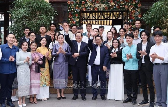 Prime Minister Pham Minh Chinh, Prime Minister Sonexay Siphandone, their wives and Vietnamese, Laos students pose for a photo in Hanoi on January 7 (Photo: VNA)