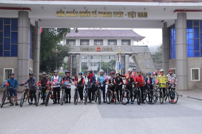 Participants in the bicycle tour pose for a photo at the Thanh Thuy International Border Gate in Ha Giang province. (Photo: baohagiang.vn)