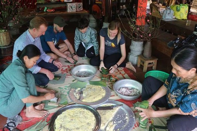 Foreign tourists experience making Chung cake (Photo: VNA)