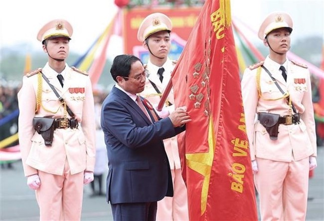 PM Pham Minh Chinh attaches the symbol of the “Hero of the People’s Armed Forces” title to the traditional flag of the Mobile Police Force. (Photo: VNA)