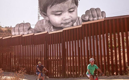Chân dung bé trai di cư khổng lồ ngó qua biên giới Mỹ - Mexico