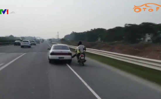 Bất chấp nguy hiểm, người đi xe máy gác chân lên ô tô trên cao tốc