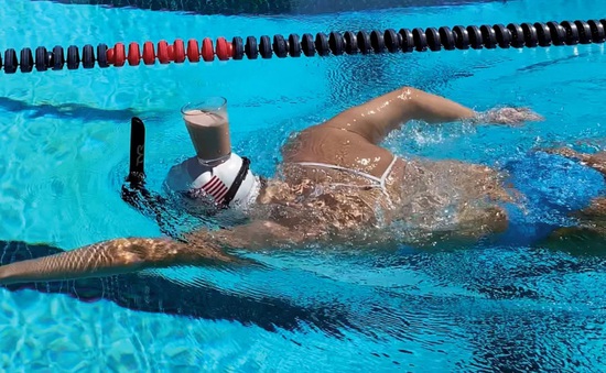 Nhà vô địch Olympic bơi với ly sữa ở trên đầu